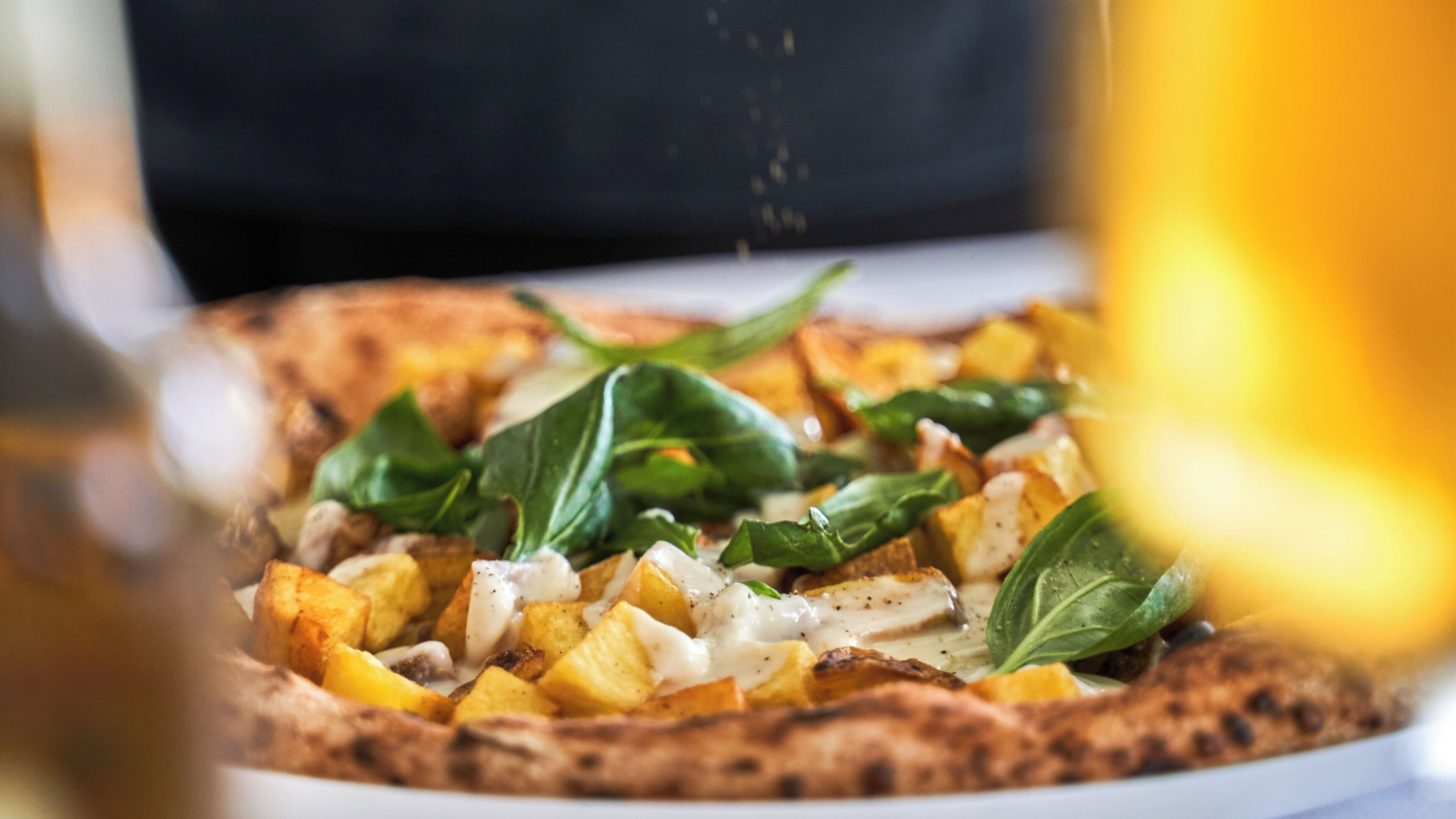 Una pizza con ingredientes visibles y un fondo desenfocado.