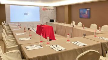 A conference room with tables, chairs, a projector screen, and a presentation on it.