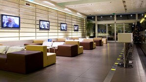 A modern lobby with seating areas, multiple screens on the wall, and a Christmas tree. - Hotel Cube (Ravenna)