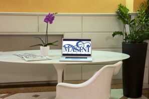 A laptop on a white table displaying "MASANI HOTEL" with a purple orchid and a potted plant beside it. - Masini Hotel (Forlì)