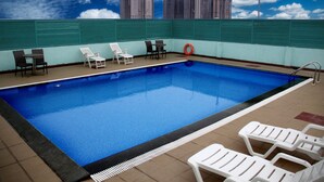 A rooftop swimming pool with lounge chairs and a view of high-rise buildings. - Gokulam Park Sabari OMR Hotel (Tirupporur)