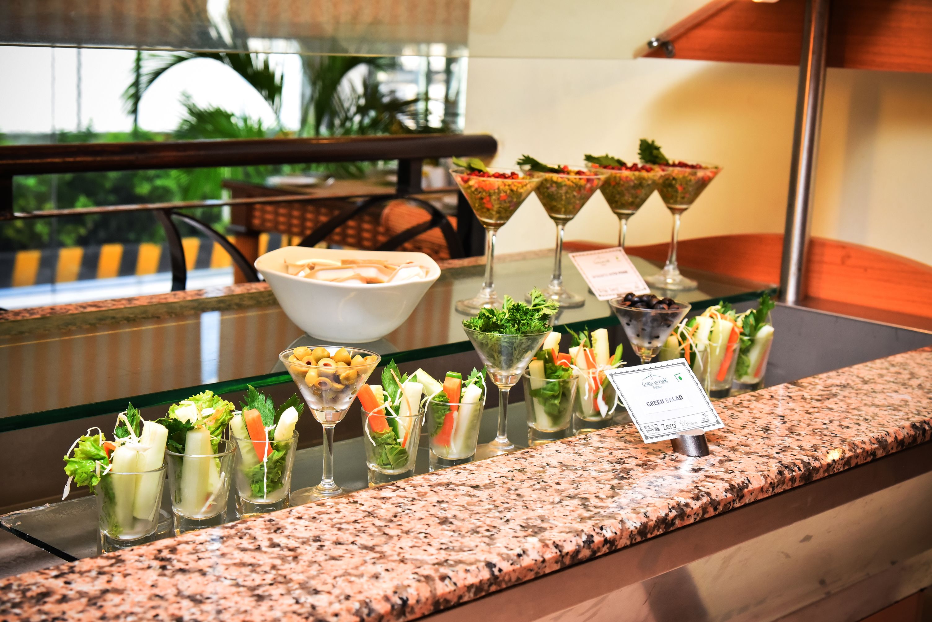 A buffet with various salads and a bowl of chips.
