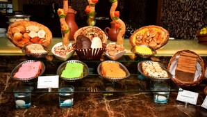 A display case with various baked goods and desserts, including cakes and bread. - Gokulam Park Sabari OMR Hotel (Tirupporur)
