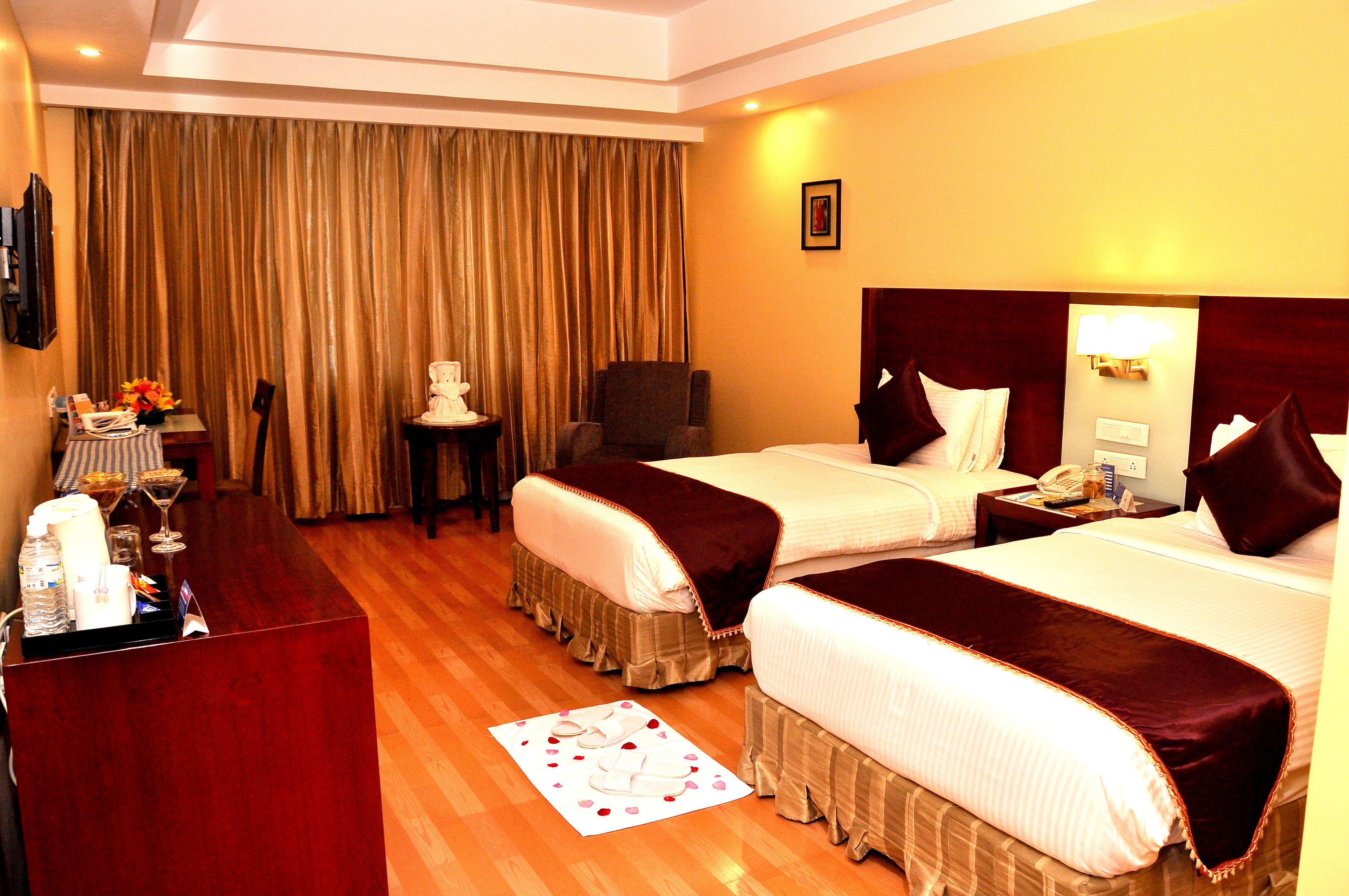A hotel room with two beds, a desk with a telephone, and a chair.