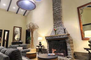 A cozy living room with a stone fireplace, comfortable seating, and a large mirror.