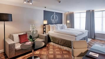 Une chambre d’hôtel avec un lit, un canapé, une petite table et une lampe.