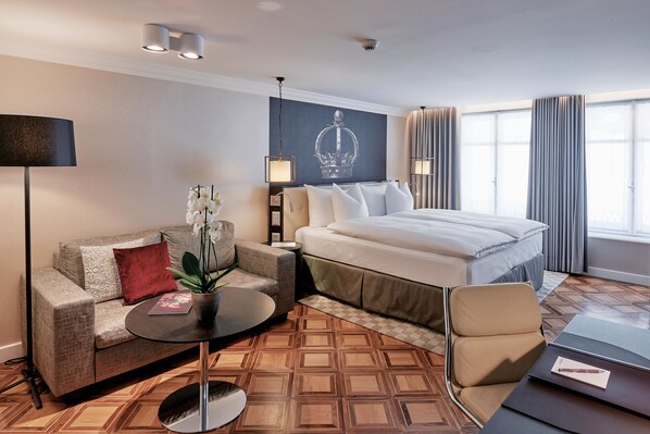 Una habitación de hotel con cama, sofá, una mesita y una lámpara.