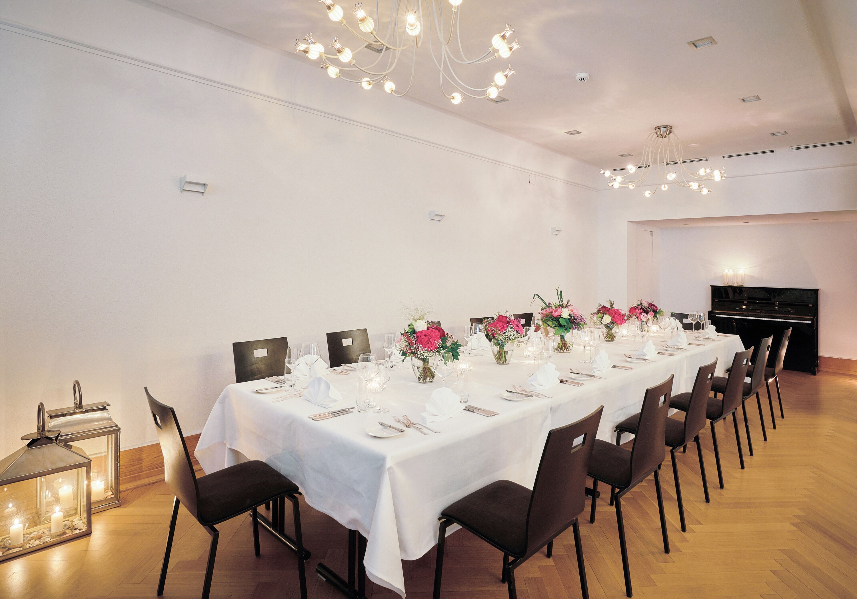 A long dining table set for a formal event with white tablecloths, chairs, and floral centerpieces.
