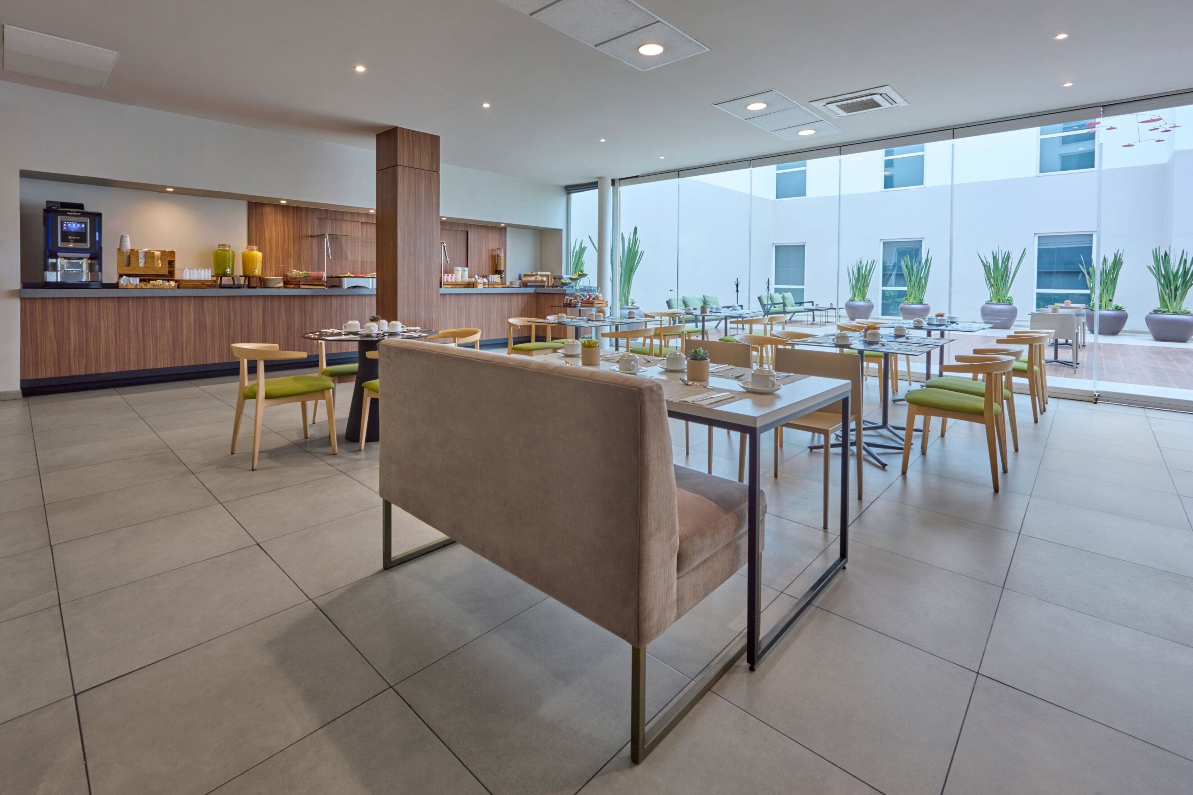 A modern dining area with a bar, tables, chairs, and potted plants.