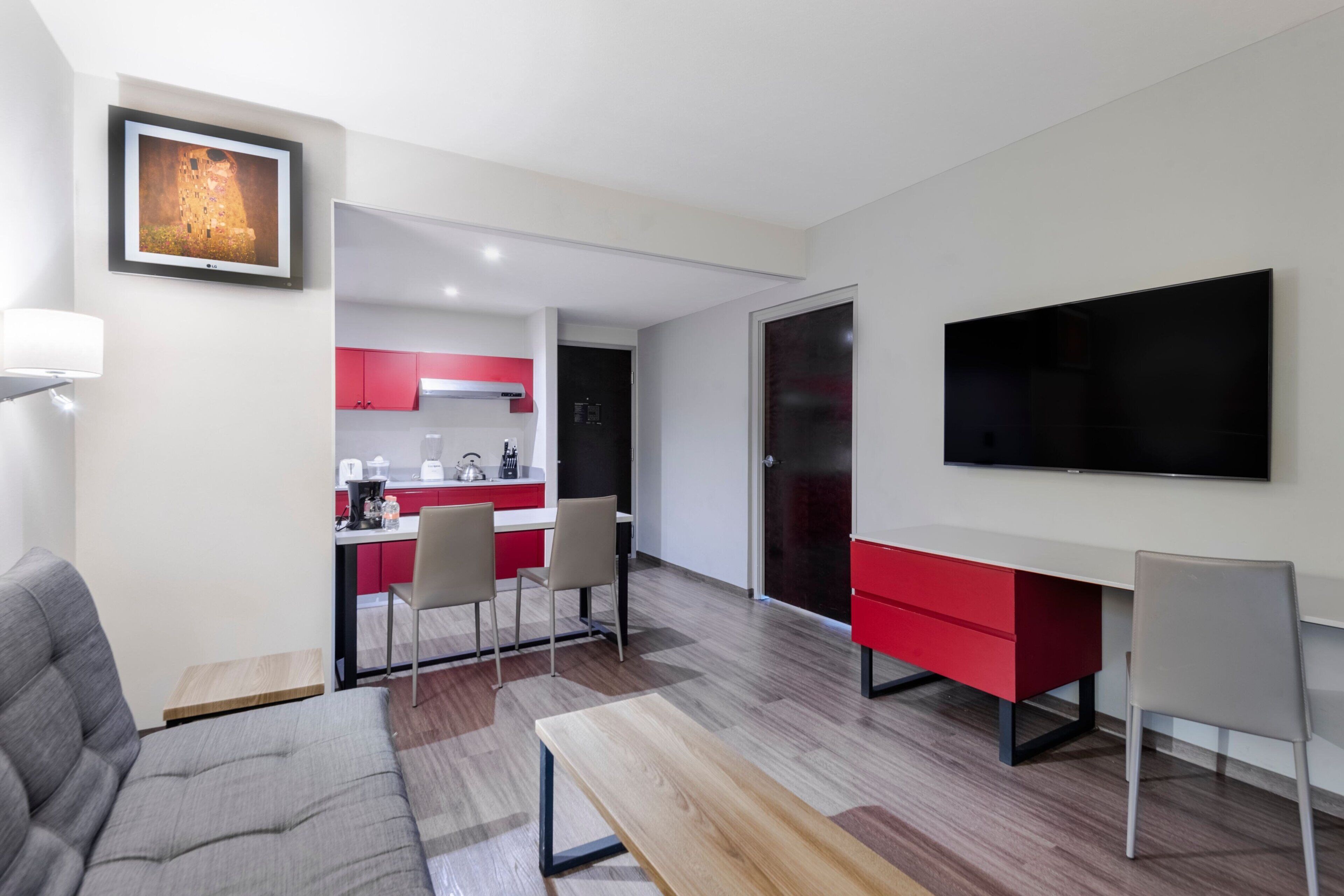 Un salon moderne avec un canapé gris, une table basse en bois et un téléviseur à écran plat fixé au mur.