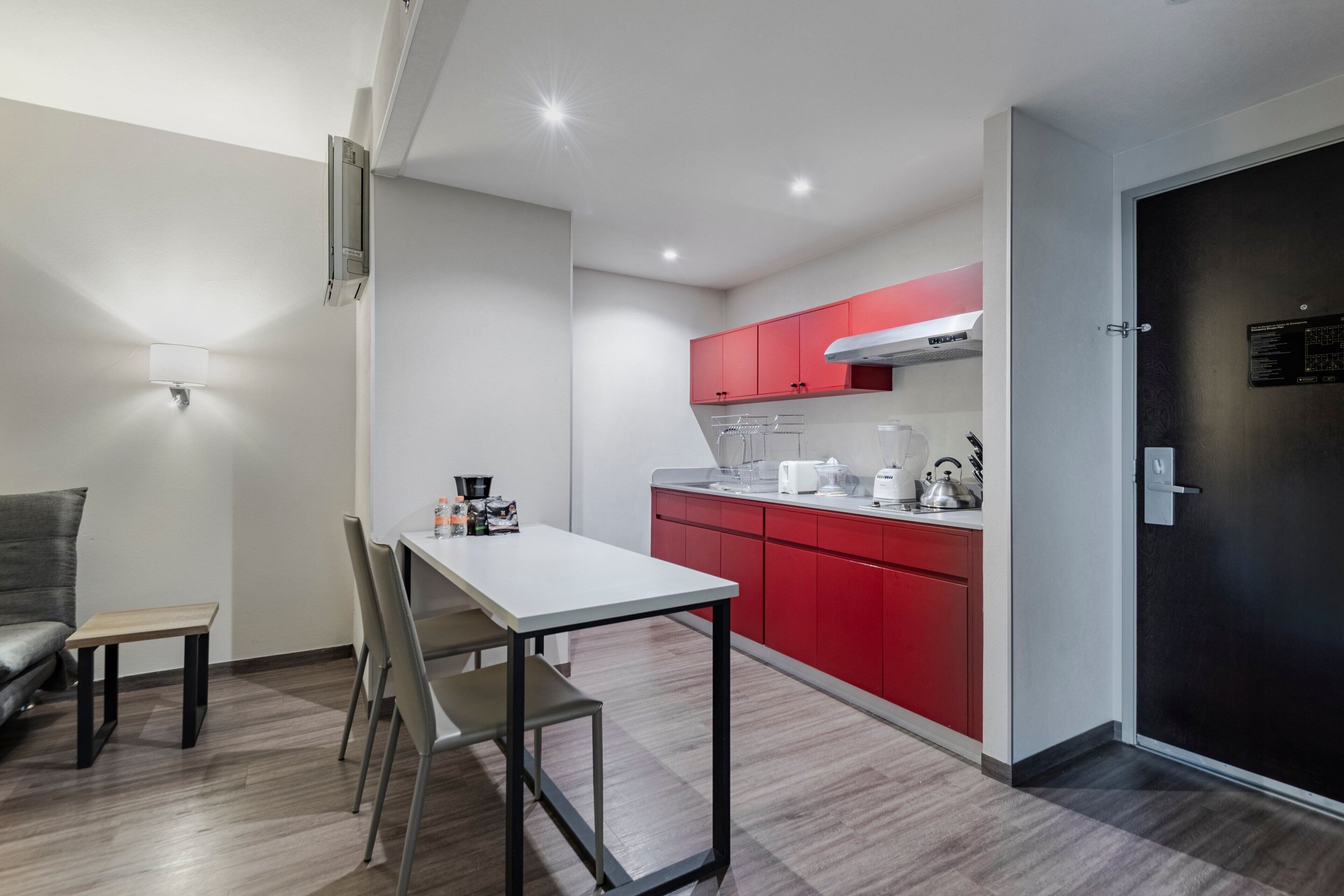 A modern kitchen with red cabinets, a white countertop, and a stainless steel range hood.