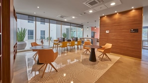 Un espacio de oficina moderno con amplios ventanales, varias mesas y sillas, y una pared de acento de madera.