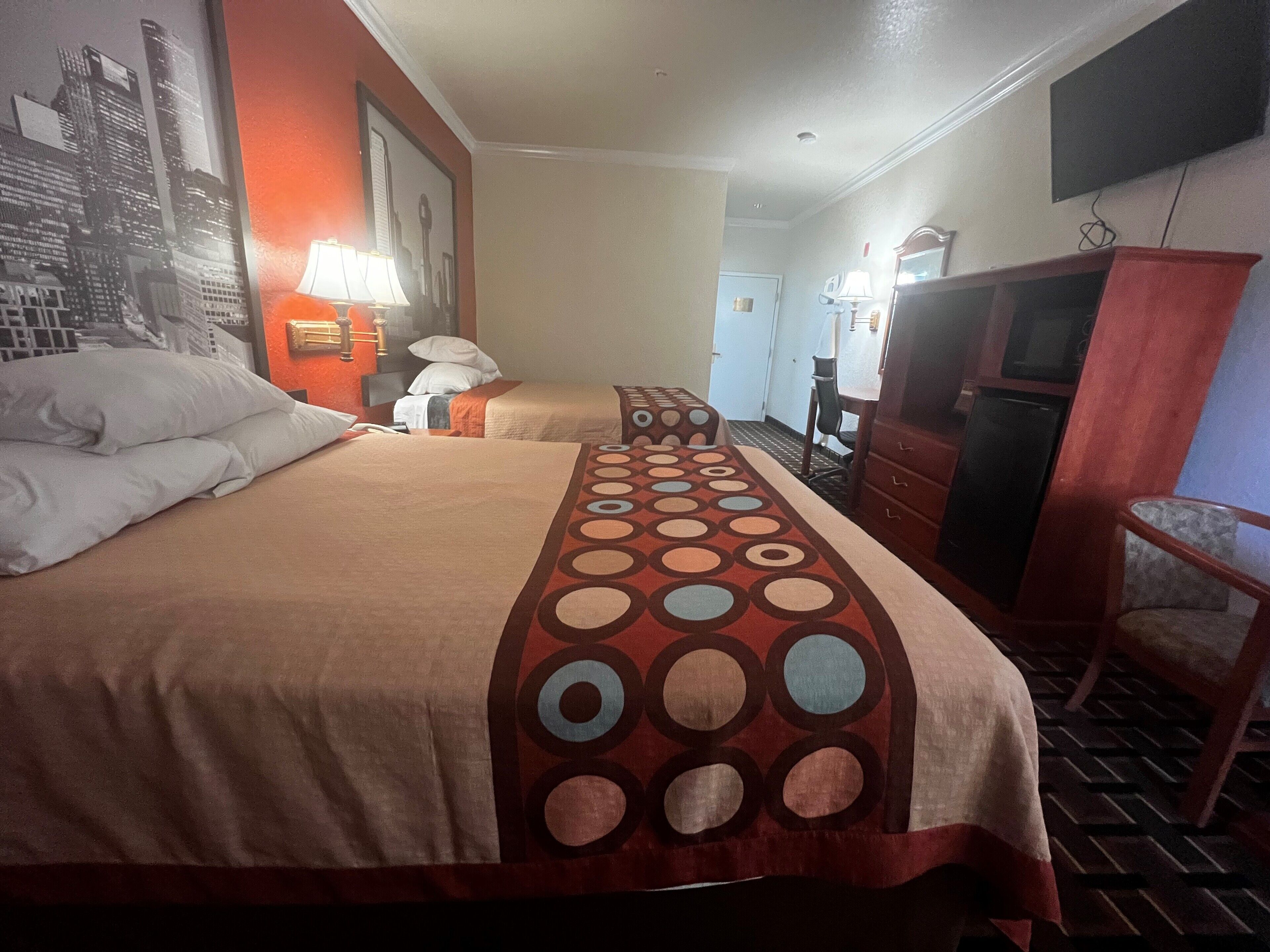 Habitación de hotel con una cama grande, dos mesitas de noche con lámparas, un televisor, un armario de madera y una silla.