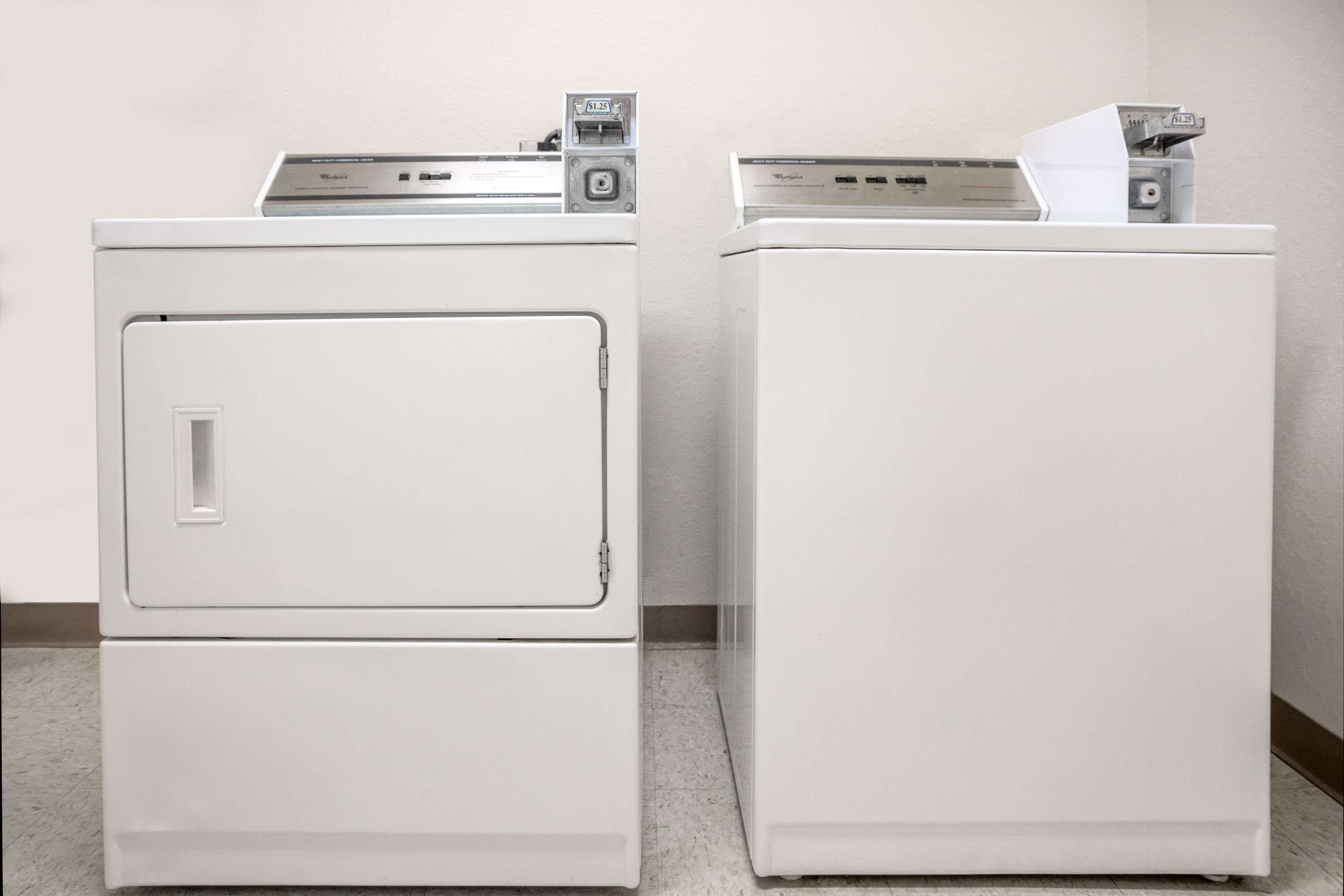 Two white front-loading washers stacked against a wall.