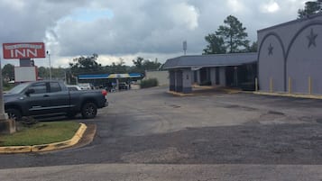Een parkeerplaats met een gebouw dat een ster op de gevel heeft, een bord voor San Augustine Inn, en een benzinestation op de achtergrond.