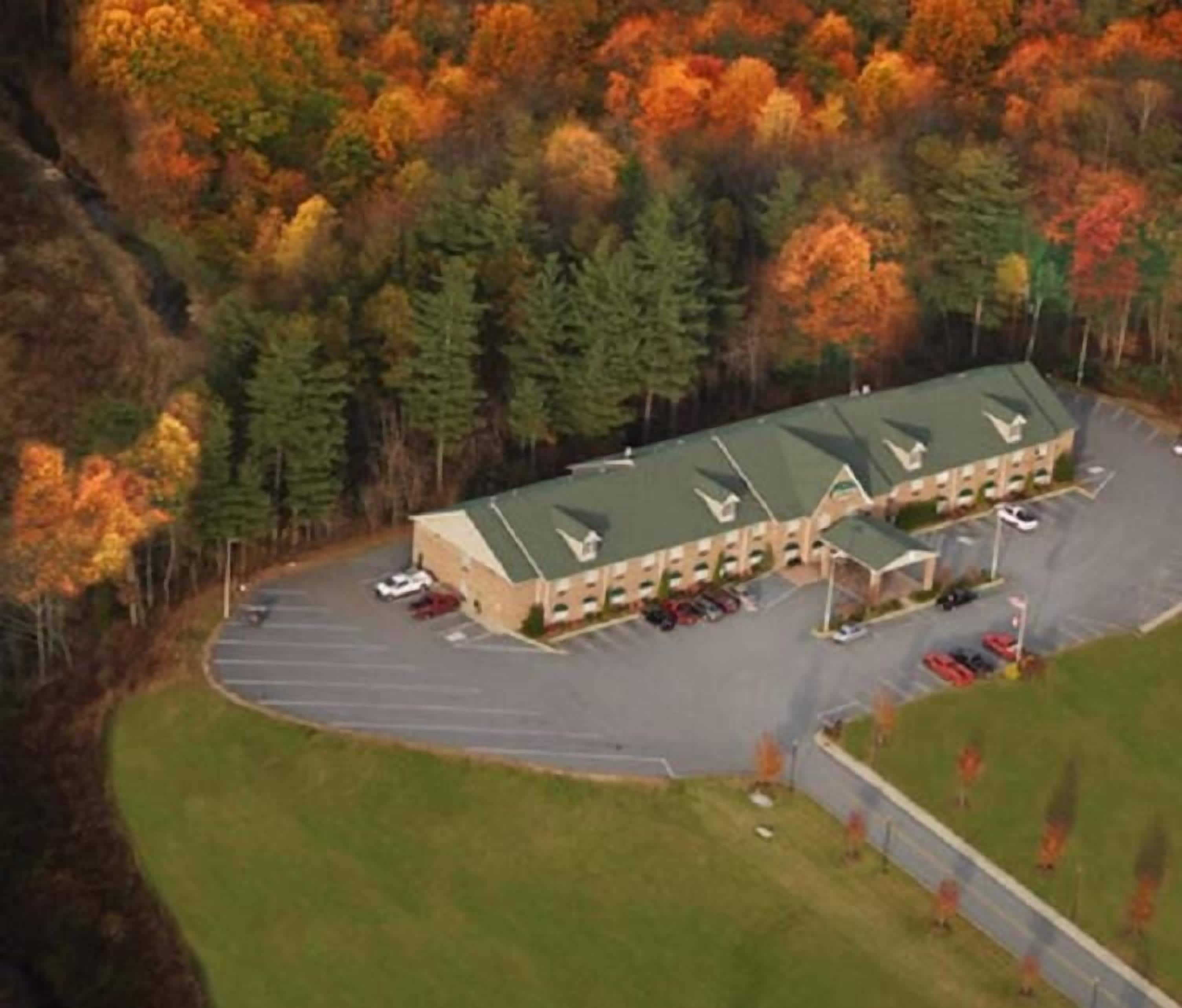 Un motel con tetto verde, diversi posti auto e un parcheggio.