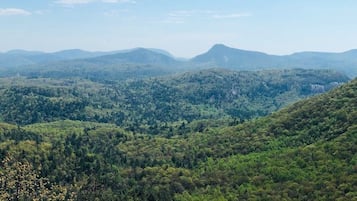 A panoramic view of a mountainous landscape with dense forest coverage and distant hills.
