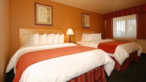 A hotel room with two beds, each with white bedding and red accents, a bedside lamp, and framed artwork on the walls. - Best Western Plus Hartford Lodge (Sutherlin)