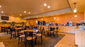 A restaurant with multiple tables and chairs, a counter with coffee machines, and a television mounted on the wall. - Best Western Plus Hartford Lodge (Sutherlin)