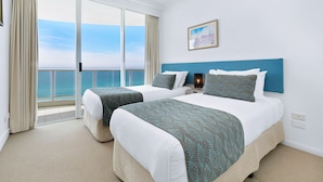 Une chambre d’hôtel avec deux lits, une grande fenêtre donnant sur la mer et un tableau accroché au mur.