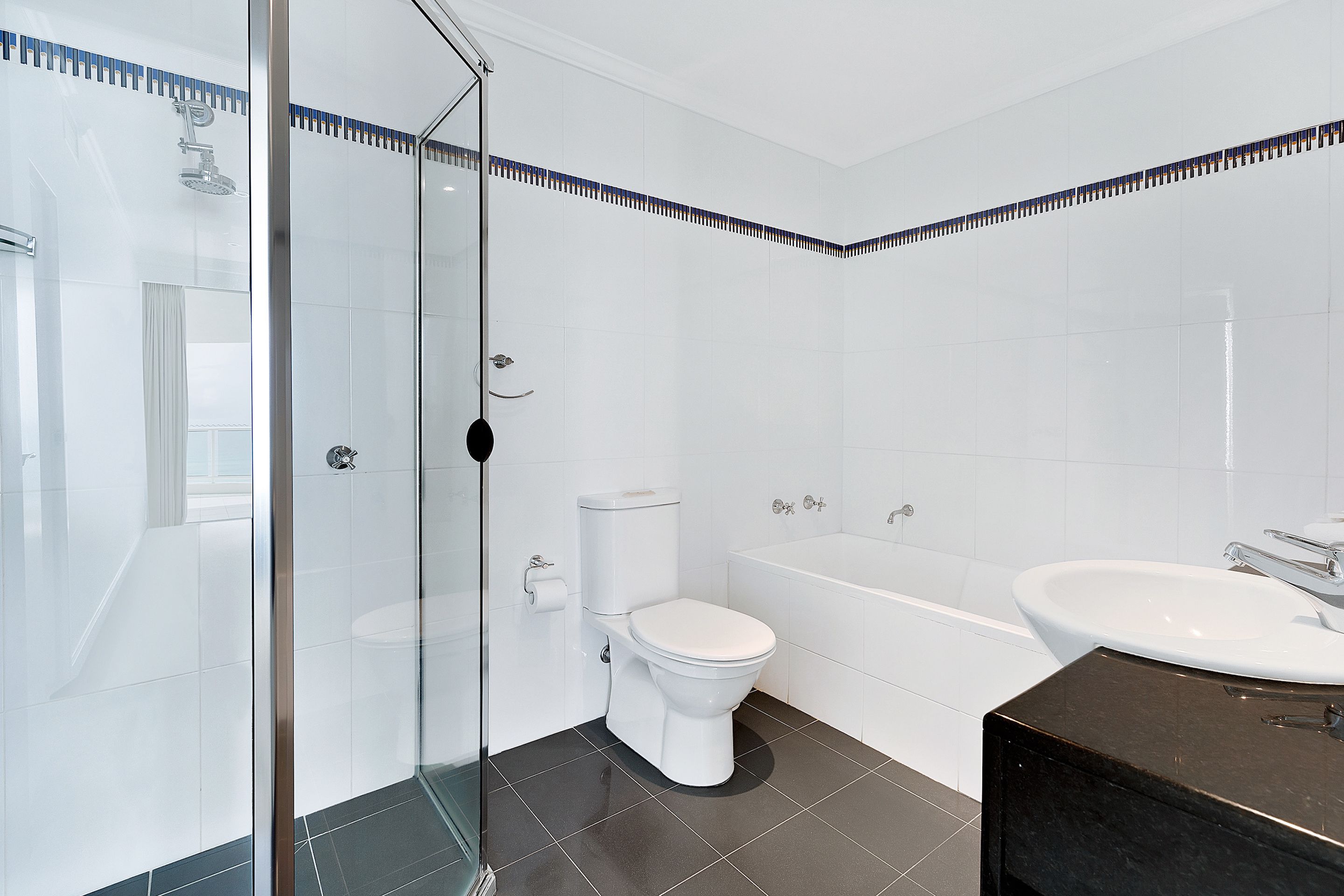 Een moderne badkamer met een douchecabine van glas, een toilet, een bad en een wastafel.