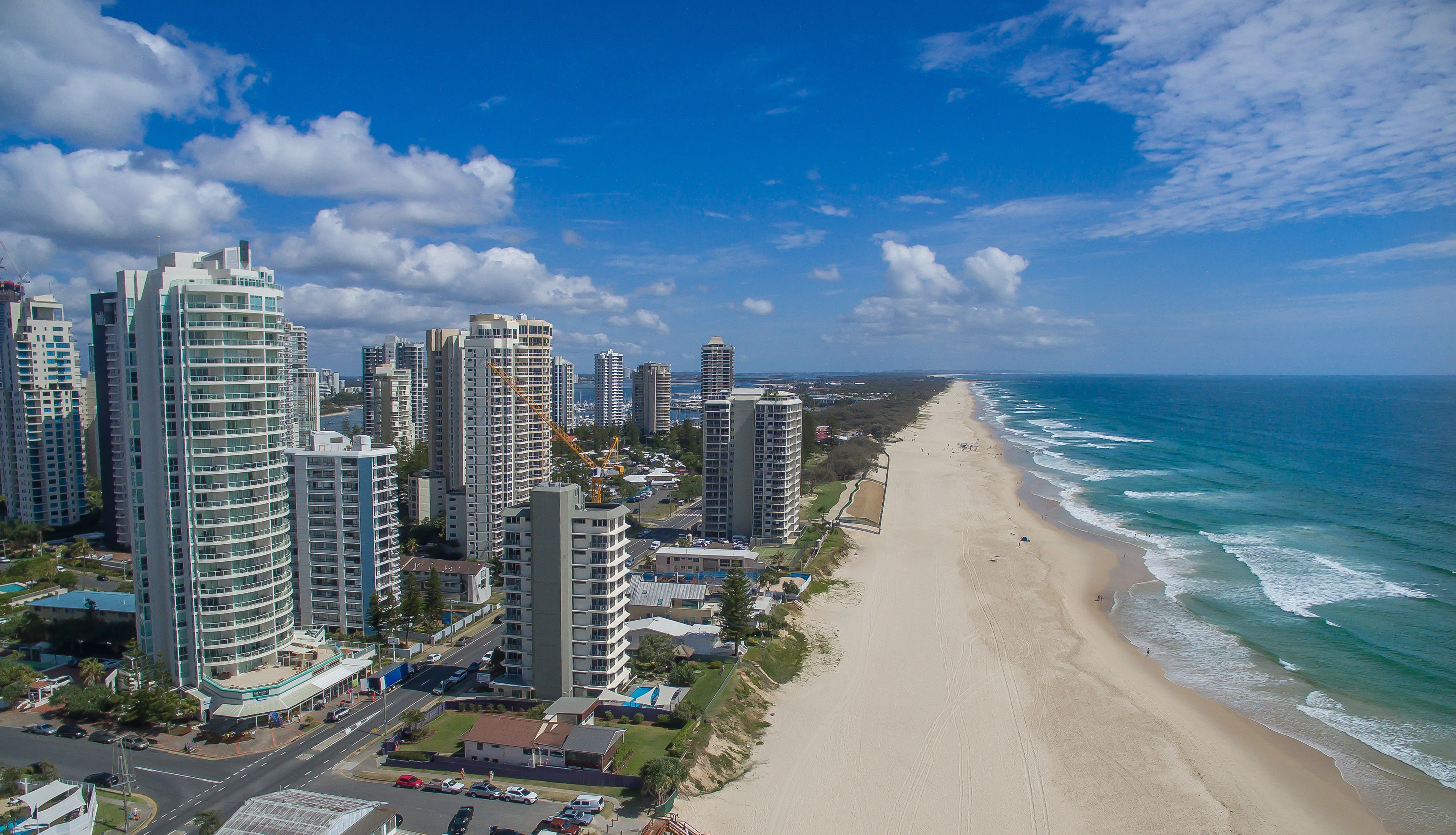 Eine Küstenstadt mit hohen Wolkenkratzern, einem Sandstrand und dem Meer.
