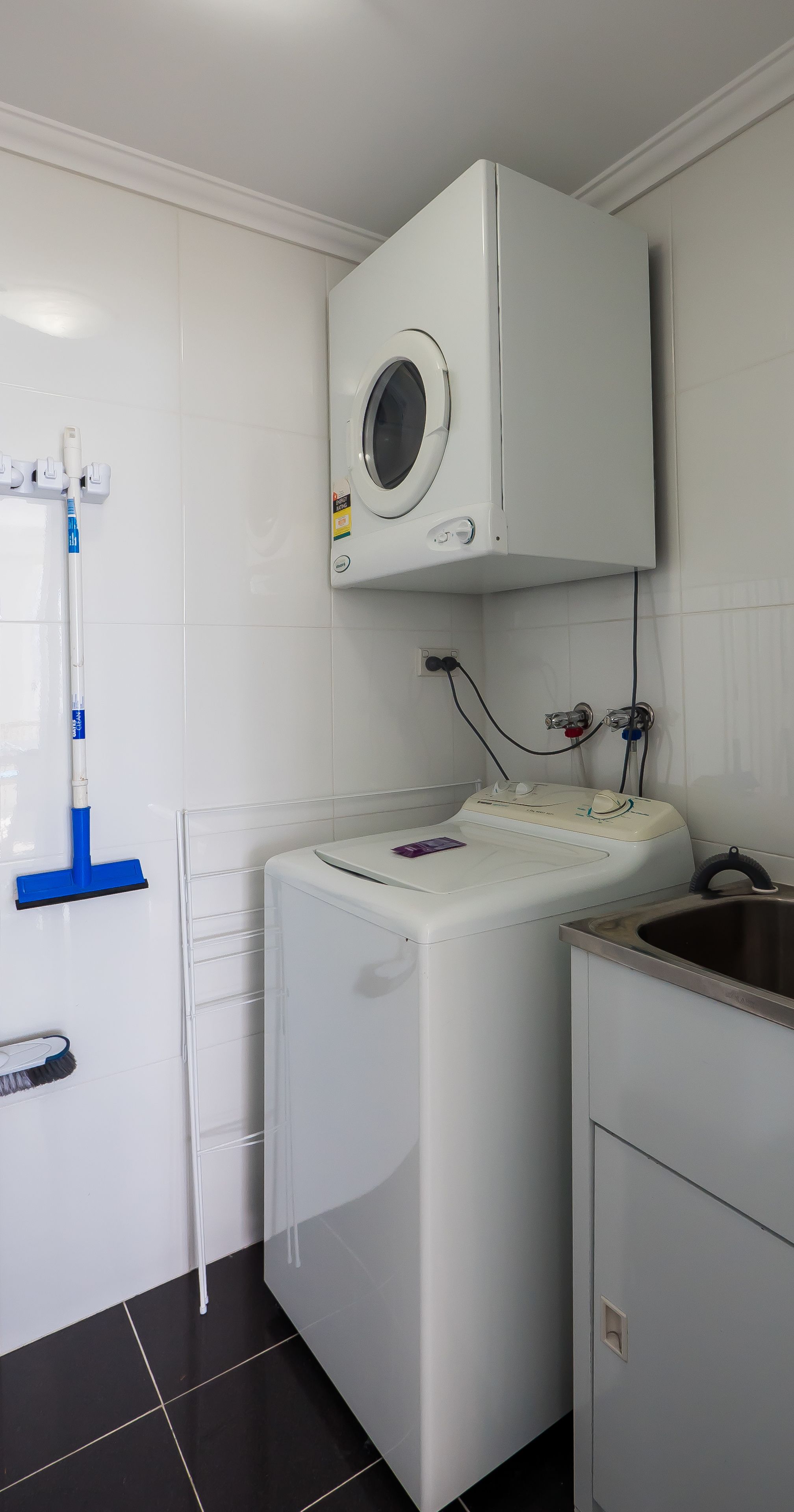 A laundry area with a washing machine, a drying rack, and a sink.