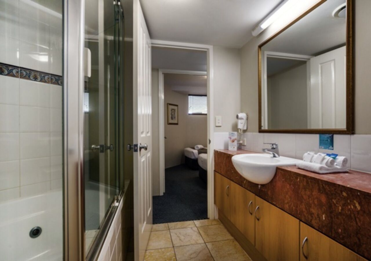 Une salle de bain dotée d’une douche à parois de verre, d’un lavabo avec un plan de travail en marbre et d’un miroir au-dessus du lavabo.
