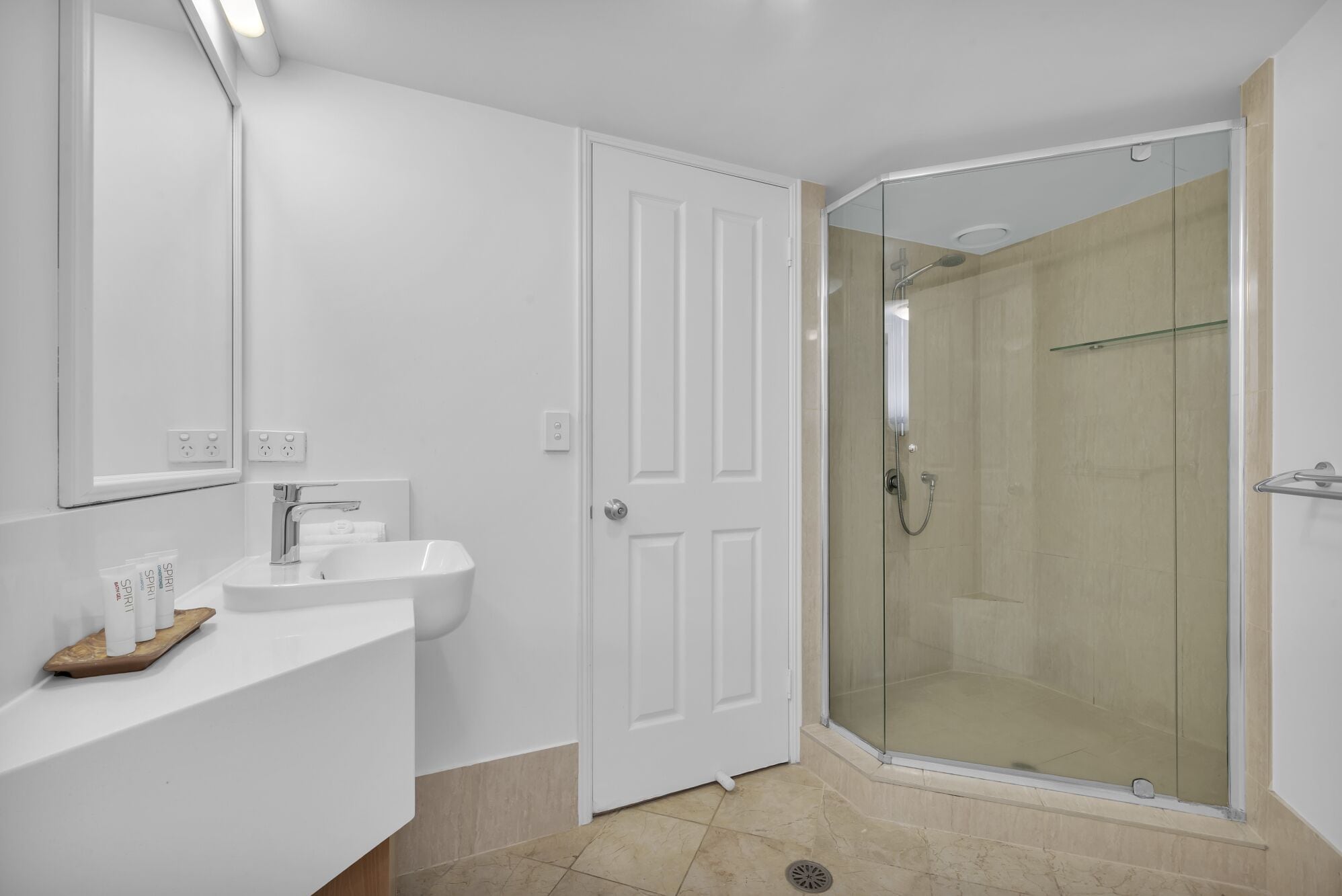 A bathroom with a white sink, mirror, and shower.