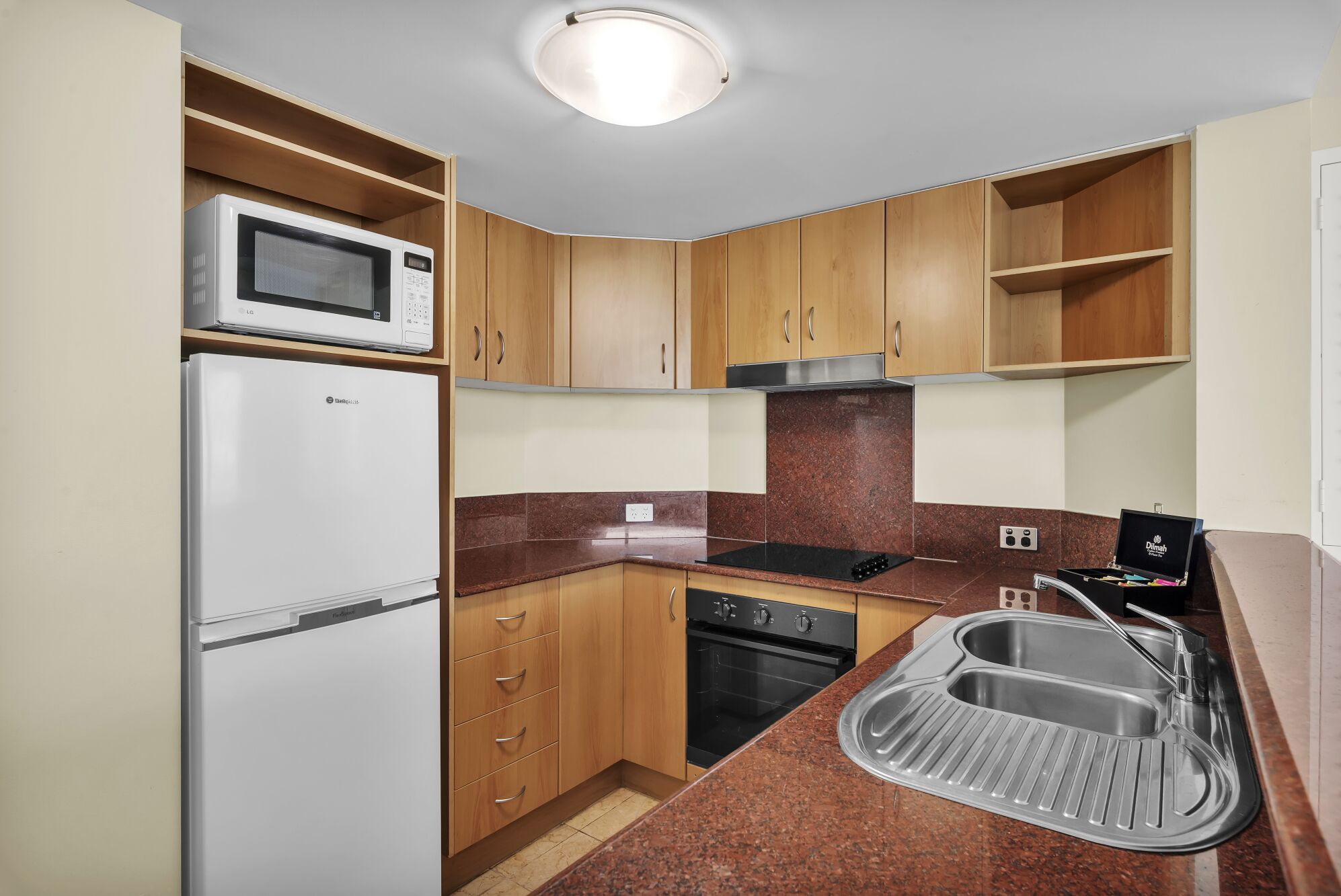 A compact kitchen with a microwave, refrigerator, stove, and sink.