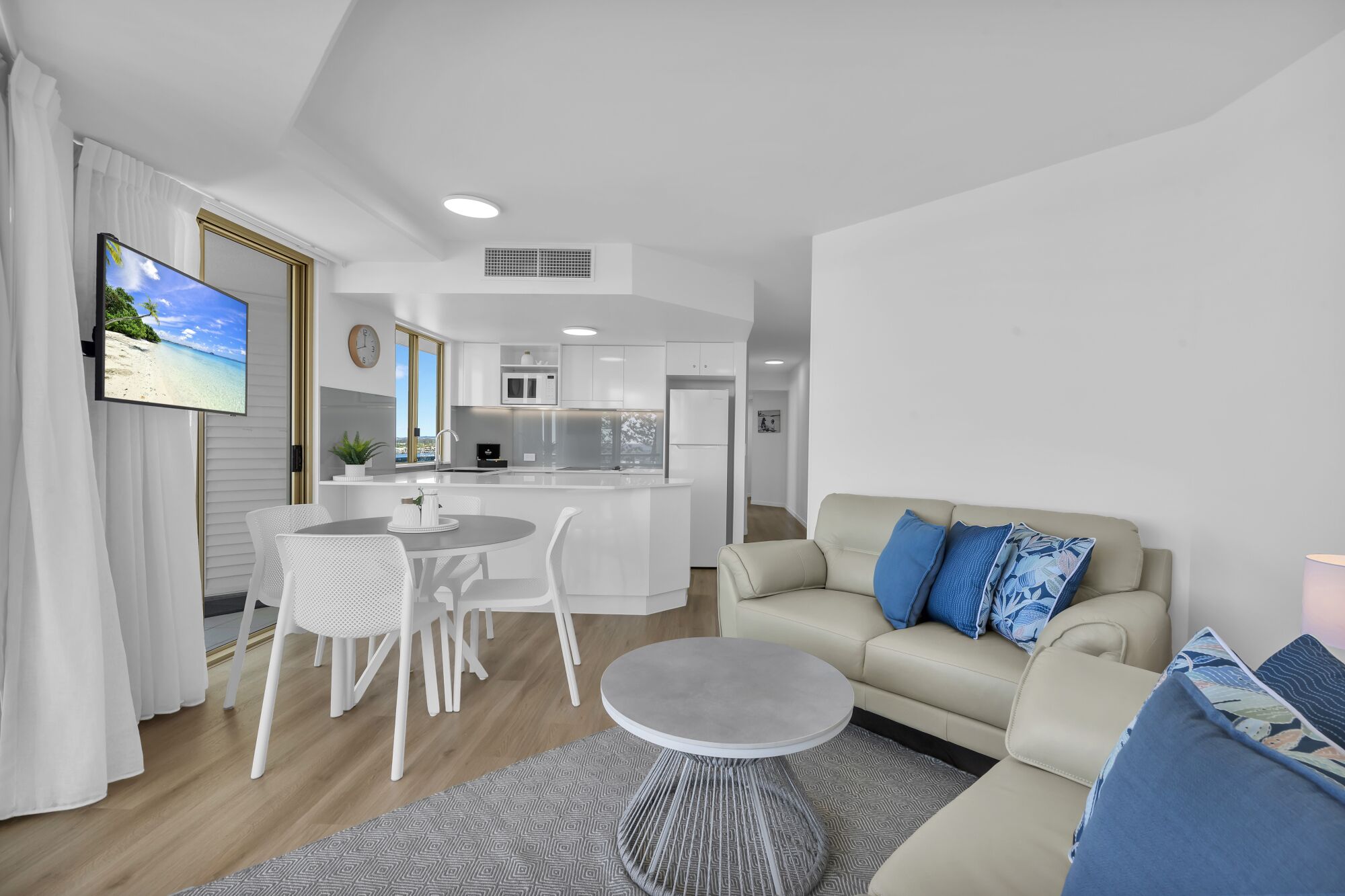 A modern living room with a sofa, a coffee table, and a dining area with chairs and a small table.