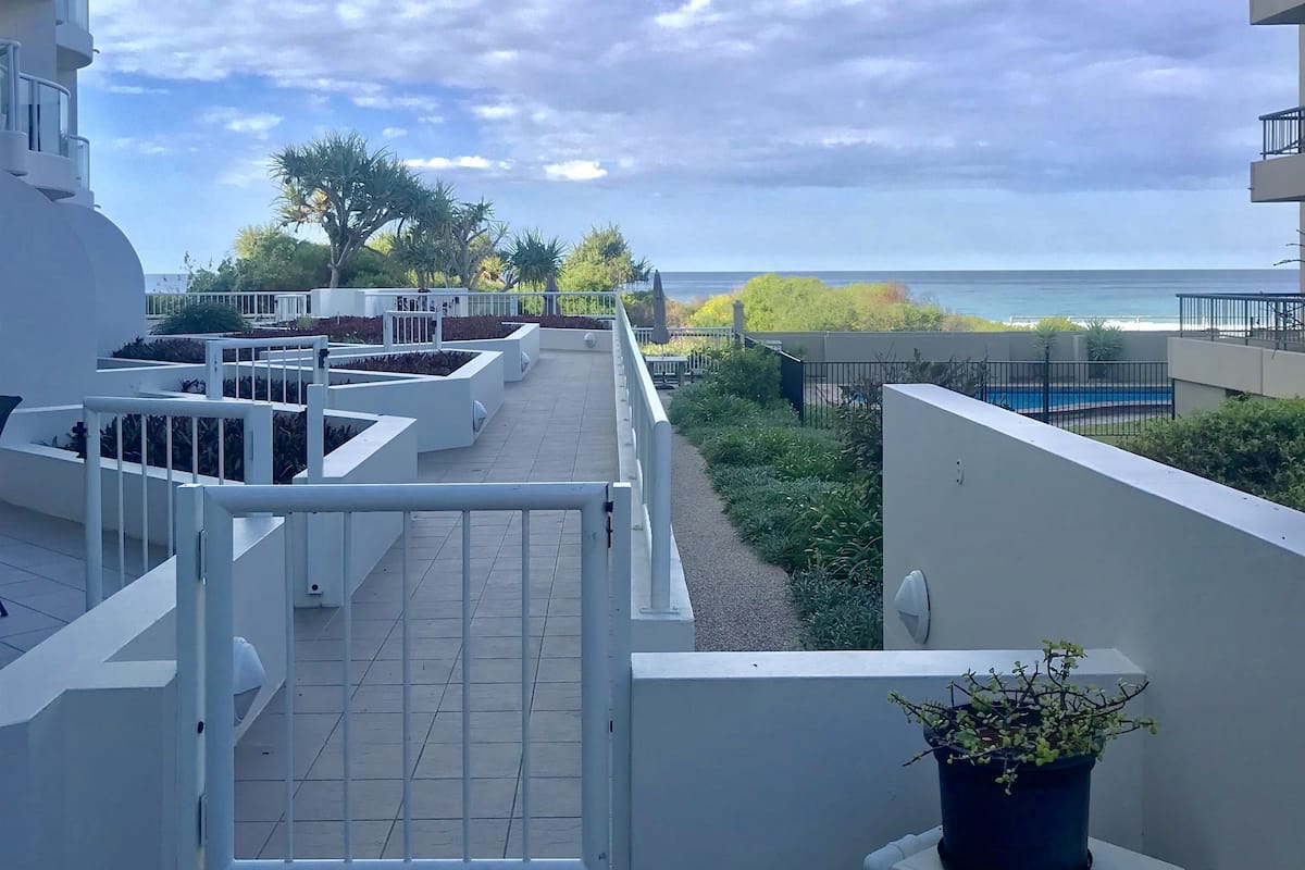A balcony with a view of the sea, a gate, and a potted plant.
