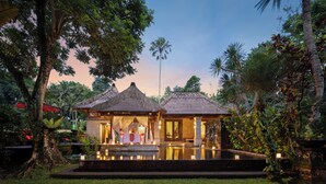 A resort with thatched-roof structures, a pool, and candle-lit pathways. - Arma Museum & Resort (Ubud)