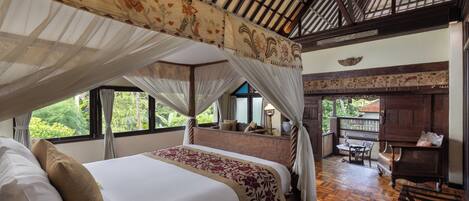 A four-poster bed with a canopy, a wooden floor, and a view of the outdoors.