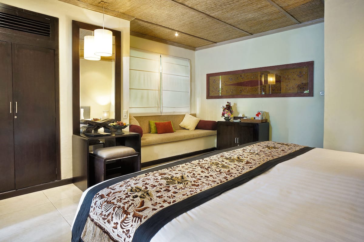 Una habitación de hotel con una cama grande, un sofá, un escritorio y un armario.