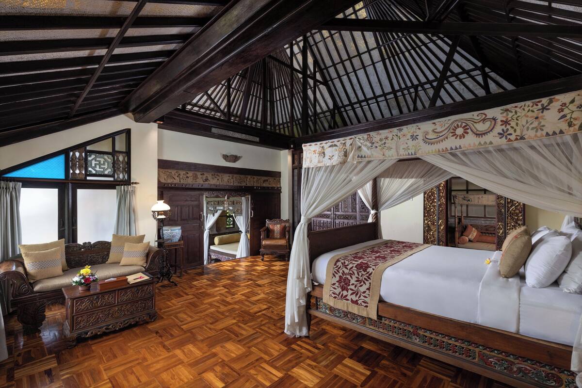 Una habitación amplia con una cama grande, un sofá y piso de madera.
