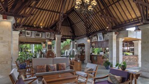 A spacious lobby with wooden furniture, a high ceiling, and framed artwork on the walls. - Arma Museum & Resort (Ubud)