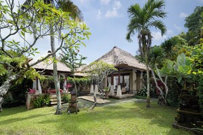 Un complexe hôtelier tropical doté de bâtiments à toits de chaume, d’une végétation luxuriante et d’un sentier en pierre.