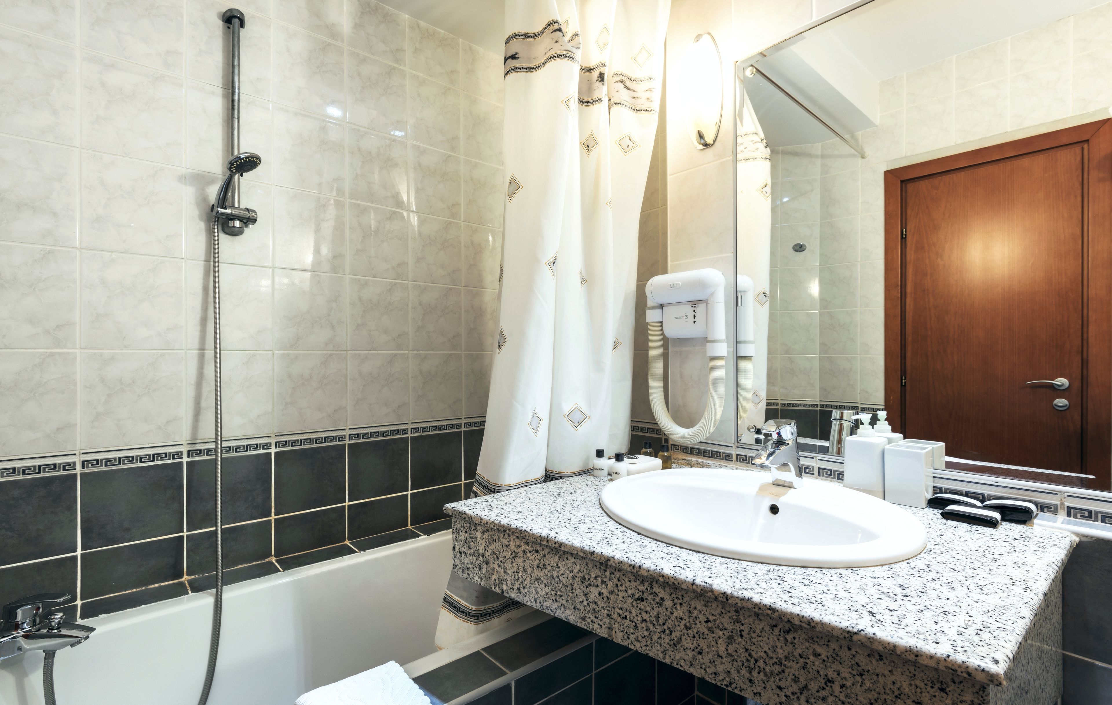 Un baño con ducha, lavamanos y espejo.