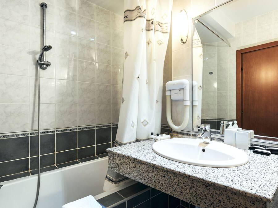 Un baño con ducha, lavamanos y espejo.