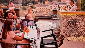 A rooftop bar with a view of historic buildings and a dome. - Hotel Arka (Skopje)