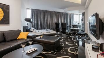 Une chambre d’hôtel moderne avec un canapé, un pouf et une petite table sur laquelle se trouve un plateau de chocolats.