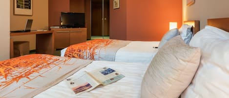 Habitación de hotel con dos camas, un escritorio con una computadora portátil, un televisor y un cuadro en la pared.