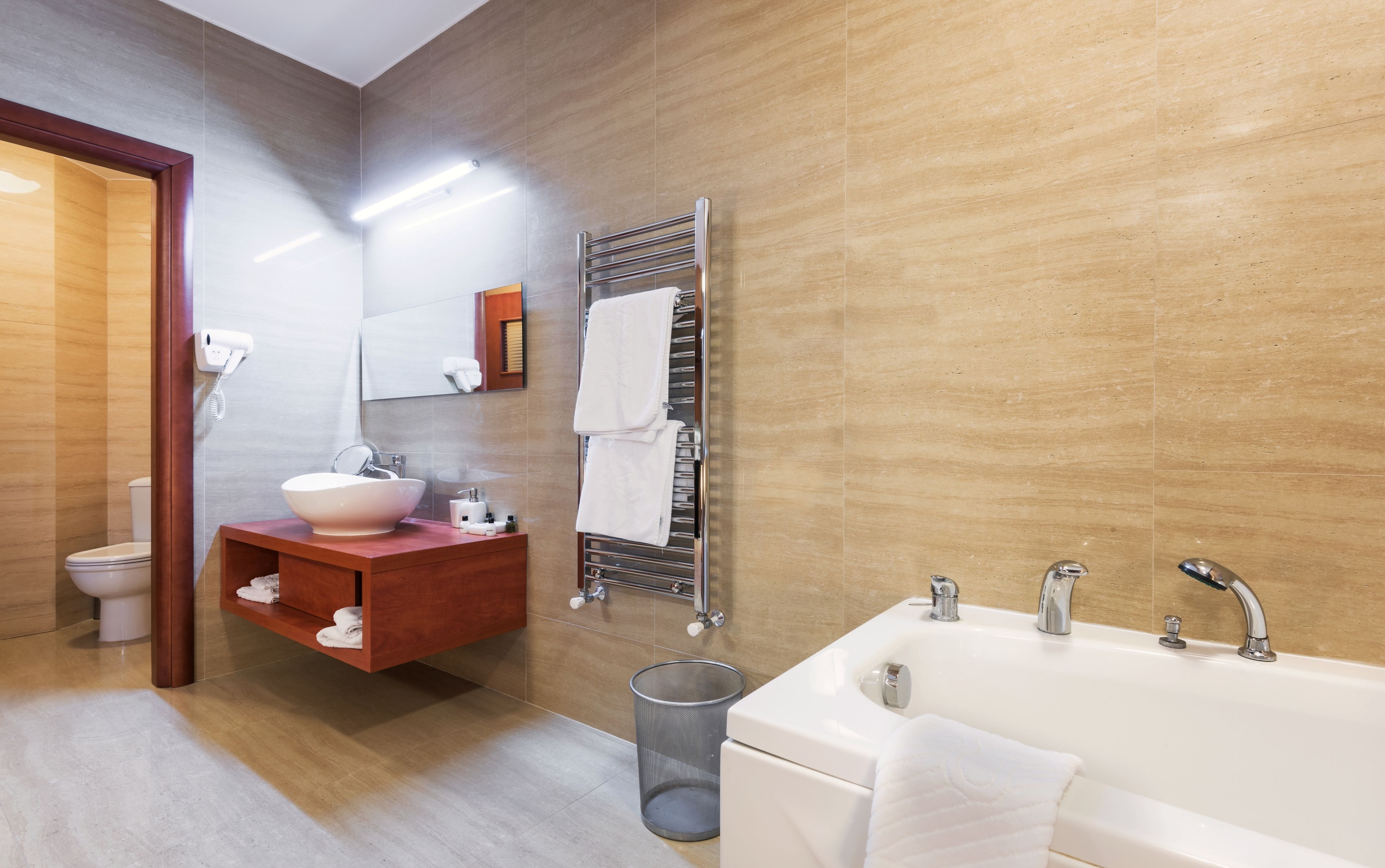 A modern bathroom with a large bathtub, a vanity with a sink, a towel rack, and a toilet.