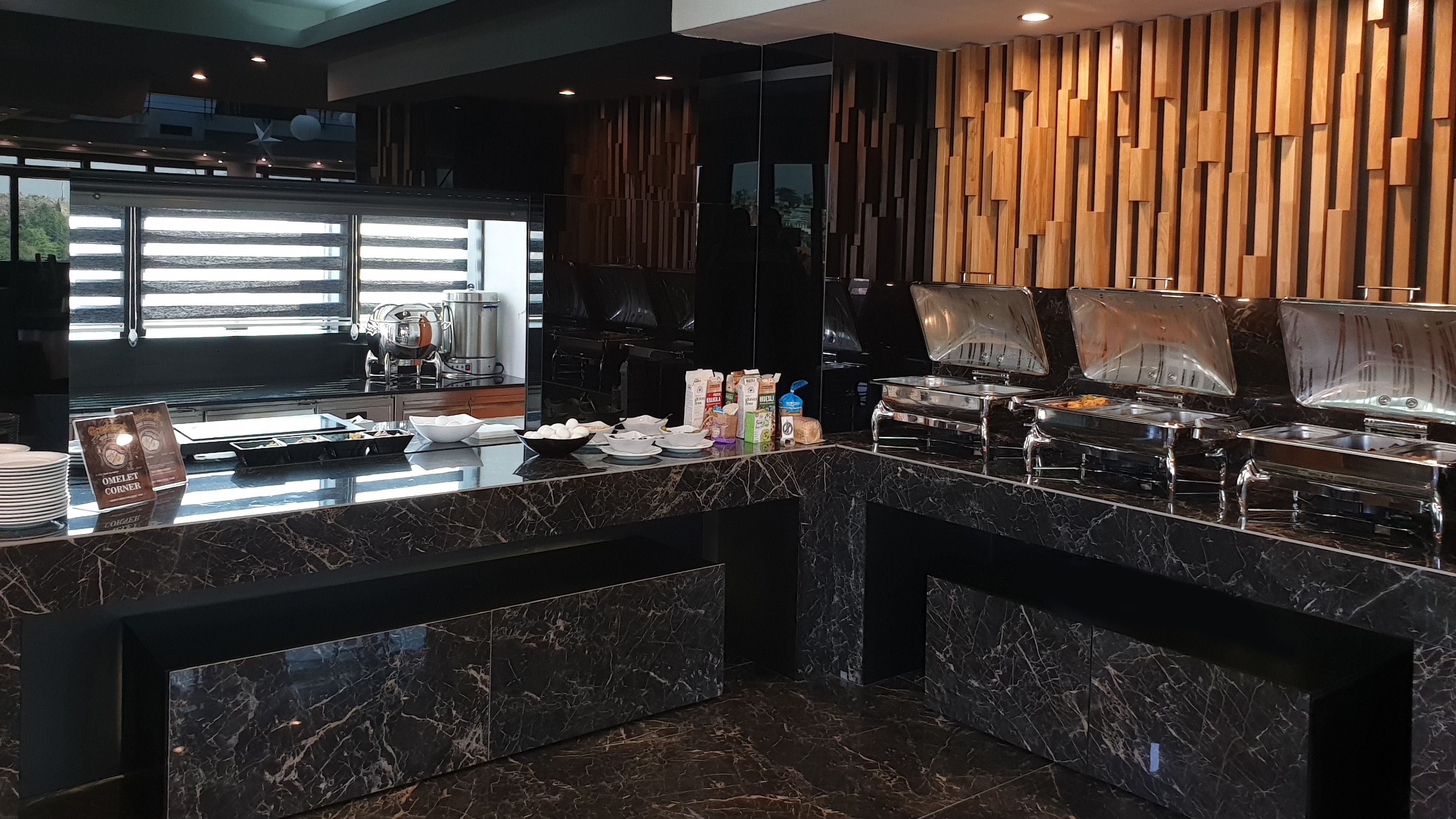 A modern kitchen with marble countertops, a coffee machine, and a buffet area with food containers.