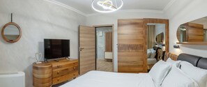 A bedroom with a bed, a TV on a wooden dresser, a mirror, and a wooden wardrobe. - Hotel Zoo Sofia (Sofia)