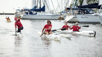 Un groupe de personnes se trouve dans un bateau sur une étendue d’eau calme, et d’autres bateaux sont amarrés au loin.