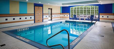An indoor swimming pool with clear water, marked depth zones, and a tiled floor.