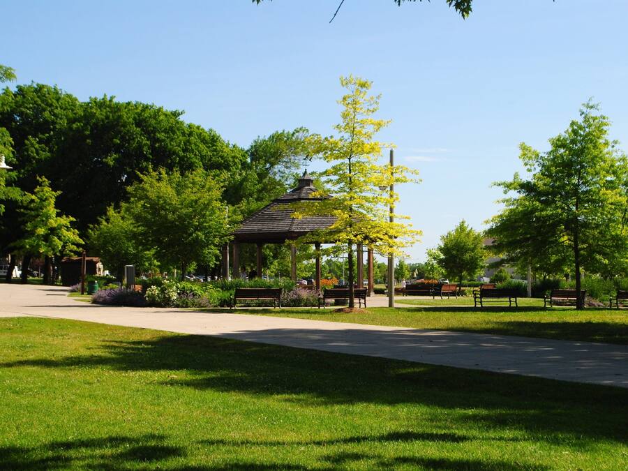 Un parque con un quiosco, bancos y un sendero.