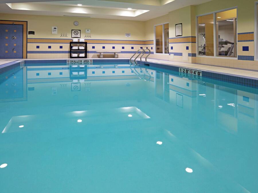 Una piscina interna con acqua cristallina, pareti piastrellate e un cartello che vieta i tuffi.